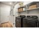 Laundry room featuring a modern black washer and dryer, shelves, and a door with mounted drying rack at 15274 W 64Th Ln # 206, Arvada, CO 80007