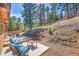 Scenic backyard patio featuring comfortable seating, a fire pit, and forest views at 22349 Natsihi Rd, Indian Hills, CO 80454