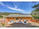 A spacious backyard offers a charming deck, modern patio seating, a fire pit, and solar panels on a log-sided home at 22349 Natsihi Rd, Indian Hills, CO 80454
