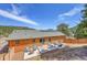 Scenic backyard featuring log-sided home with modern patio and deck, solar panels, and mountain views at 22349 Natsihi Rd, Indian Hills, CO 80454