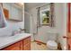 Cozy bathroom featuring a window providing natural light, wood cabinets, and a shower with a curtain at 22349 Natsihi Rd, Indian Hills, CO 80454
