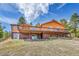 A beautiful view of the home's back exterior with a sprawling deck from the walkout basement at 22349 Natsihi Rd, Indian Hills, CO 80454
