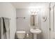 Cozy bathroom featuring a pedestal sink, toilet, decorative mirror, and a towel bar with plush gray towels at 1151 N Marion St # 104, Denver, CO 80218