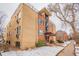 Three story brick apartment building with large windows and awnings at the entry way in a snow covered landscape at 1151 N Marion St # 104, Denver, CO 80218