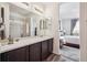 Bright bathroom with dual mirrors, a vanity with dark wood cabinetry, and en-suite bedroom access at 95 S Edge Cliff St, Castle Rock, CO 80104