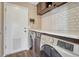 Functional laundry room featuring modern machines, subway tile, and ample countertop space at 18668 E Vassar Dr, Aurora, CO 80013