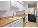 Bright kitchen with white cabinets, wooden countertops, and modern appliances at 1060 S Parker Rd # 19, Denver, CO 80231