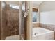 Bright bathroom featuring a tile shower with glass door and a jetted tub with tile surround at 12427 James Ct, Broomfield, CO 80020