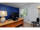 Bedroom with a wooden desk, blue accent wall, neutral carpet, and a bright window at 13441 Cherry St, Thornton, CO 80241