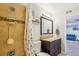 A well-lit bathroom featuring a tiled shower, decorative mirror and brown vanity at 3550 S Harlan St # 335, Denver, CO 80235