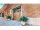 Charming brick building exterior with large wooden garage door and potted evergreen plants at 1510 Wazee St # 3, Denver, CO 80202