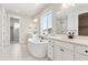 Bright bathroom with a standalone tub, double sinks, white cabinetry, and modern fixtures at 1714 Morgan Dr, Erie, CO 80516