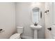 A half-bathroom featuring a pedestal sink, toilet, and oval mirror at 1714 Morgan Dr, Erie, CO 80516