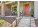 Inviting front porch with stylish brick accents, leading to a vibrant red front door and manicured landscaping at 504 E Dry Creek Pl, Littleton, CO 80122