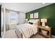 Serene bedroom with a green accent wall, natural light, and stylish furnishings at 17117 W 91St Ln, Arvada, CO 80007