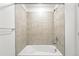 A bright white shower and tub featuring tile walls, clean fixtures, and neutral finishing at 17117 W 91St Ln, Arvada, CO 80007