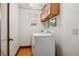 Functional laundry room with white appliances, wood floors, and overhead storage at 740 Carr St, Lakewood, CO 80214