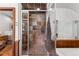 Shower with stone tile walls, stone floors, glass door and wood trim detail at 740 Carr St, Lakewood, CO 80214