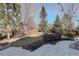 Landscaped backyard with mature trees and a stone retaining wall at 14032 Park Cove Dr, Broomfield, CO 80023