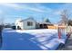 Ranch home with snowy front yard and fenced area at 6661 Clermont St, Commerce City, CO 80022