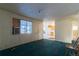 Living room with teal carpet, window, and view to kitchen at 6661 Clermont St, Commerce City, CO 80022