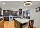 Modern kitchen featuring dark cabinets, stainless steel appliances, island, and black marble backsplash at 9135 Bellaire St, Thornton, CO 80229