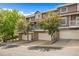 Townhome complex featuring garages, stone accents, and well-maintained landscaping with mature trees at 6813 W Yale Ave, Lakewood, CO 80227