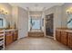 Modern bathroom featuring a glass shower, tile floors, double vanity, and soaking tub under a window at 575 Howling Cir, Elizabeth, CO 80107