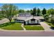 Well-maintained ranch-style home featuring a lush front lawn, mature trees, and an extended driveway leading to a two-car garage at 6220 E 5Th Ave, Denver, CO 80220