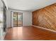 Spacious bedroom featuring a wood accent wall, balcony access, and laminate flooring at 3662 S Granby Way # J05, Aurora, CO 80014