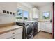 Laundry room with modern washer and dryer, cabinet storage, folding table and a bright window at 6338 Spotted Fawn Run, Littleton, CO 80125
