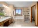 Luxurious bathroom features a tub under a window, walk-in shower, vanity, and tile flooring at 7202 Snow Peak Ct, Niwot, CO 80503