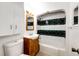 Bathroom with wood vanity, toilet, and shower/tub combo featuring white and black tile design at 3125 W Ford Pl, Denver, CO 80219