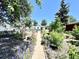 Lush garden path leads to the house from the backyard, surrounded by mature trees and greenery at 1270 Havana St, Aurora, CO 80010