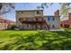 Back exterior of a two-story home with a deck, patio, and green lawn at 6336 S Newland Ct, Littleton, CO 80123