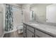 Bright bathroom featuring a shower-tub combo with white tile surround and a gray vanity with granite countertop at 1365 W 67Th Pl, Denver, CO 80221