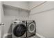 Modern laundry room with gray wood-look flooring and front-load washer and dryer set below a shelf with hanging rod at 1365 W 67Th Pl, Denver, CO 80221