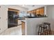 Kitchen area with an island bar, black appliances, and white tile flooring at 8199 Welby Rd # 3707, Denver, CO 80229