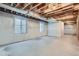 Unfinished basement featuring concrete floors, visible beams, and two windows for natural light at 2627 S Acoma St, Denver, CO 80223