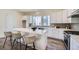 Bright kitchen features white cabinets, marble countertops, island seating, stainless appliances, and wood flooring at 682 Belay St, Erie, CO 80516