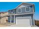 Charming blue two-story home with a white garage door and covered entryway at 2212 Crosswind St, Fort Lupton, CO 80621