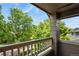 Outdoor balcony view featuring a gray wooden railing, lush green trees, and blue skies at 5755 W Berry Ave, Denver, CO 80123