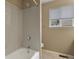 Bright bathroom featuring a tub with white tile surround and shower, as well as natural light from the window at 5755 W Berry Ave, Denver, CO 80123