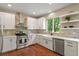 Bright kitchen features white cabinets, stainless steel appliances, and a farmhouse sink with warm wood floors at 5755 W Berry Ave, Denver, CO 80123