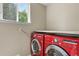 Bright laundry room with red washer and dryer, window, and storage shelf at 5755 W Berry Ave, Denver, CO 80123