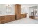Bright bathroom featuring dual vanities, wooden cabinetry, and marble floors at 73 Glenmoor Dr, Cherry Hills Village, CO 80113