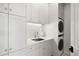 Bright laundry room featuring white cabinetry, subway tile backsplash, and a convenient stacked washer and dryer unit at 73 Glenmoor Dr, Cherry Hills Village, CO 80113