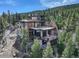 Stunning multi-level home boasting stone accents and expansive decks with mountain views nestled among lush trees at 180 Outpost Ln, Evergreen, CO 80439