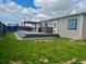 Wide view of a landscaped backyard featuring an outdoor dining area and well-maintained lawn at 6201 S Vanderhoof St, Bennett, CO 80102