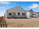 Back of house with white siding, stone accents, large windows, and an unfinished yard at 24593 E 34Th Ave, Aurora, CO 80019
